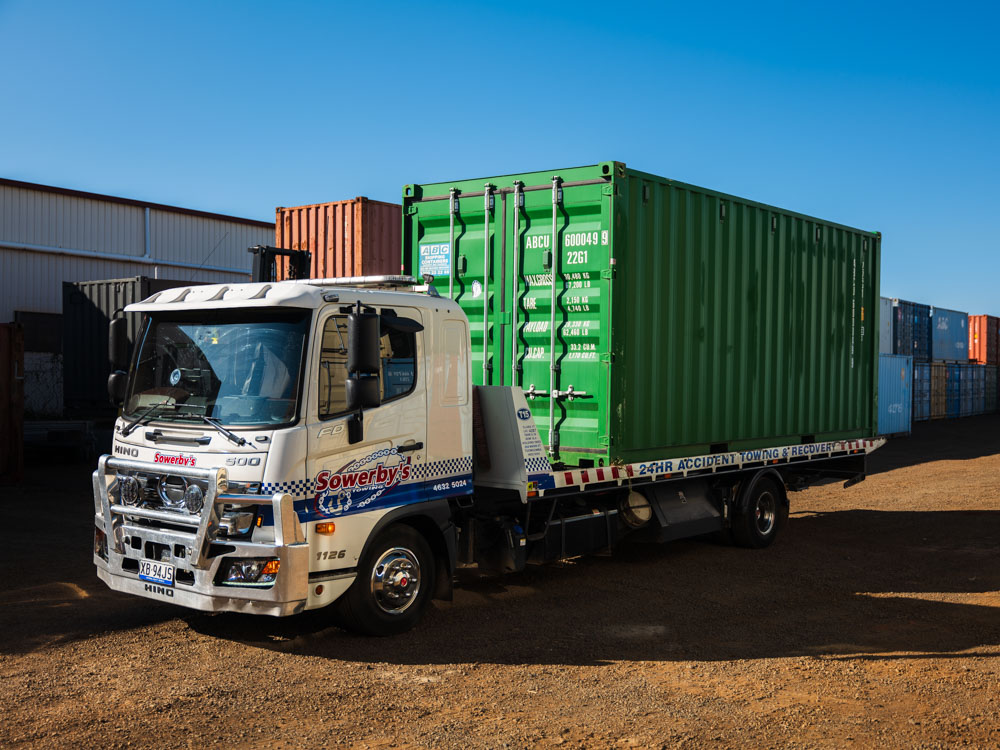 ABC tilt-tray truck delivering a container